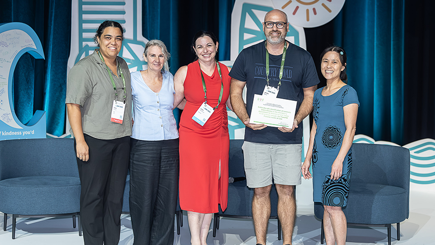 Staff members standing on stage with award certificate