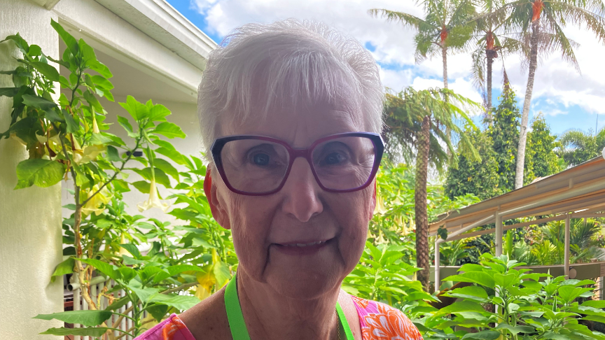Close up of elderly woman's face with garden greenery in the background
