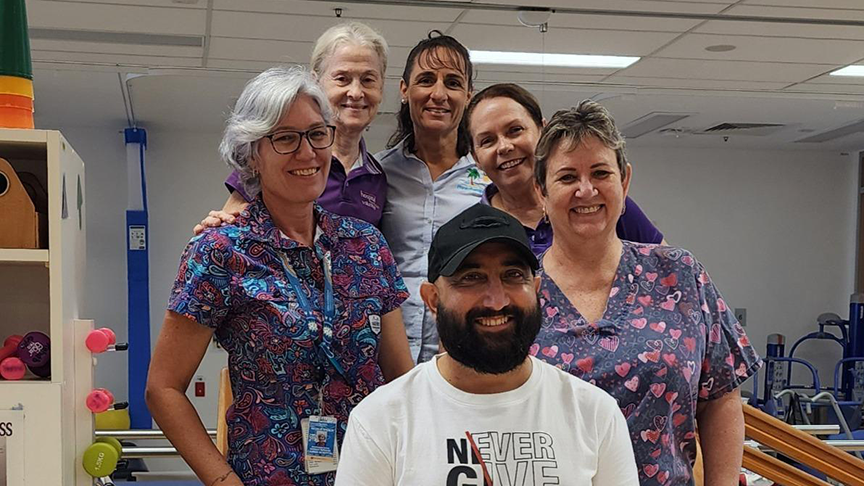 Four female clinicians standing behind male patient inside the cardiac conditioning gym
