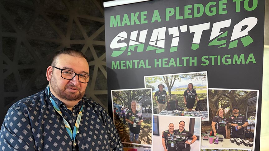Man standing next to pull up banner that says 'make a pledge to shatter mental health stigma'