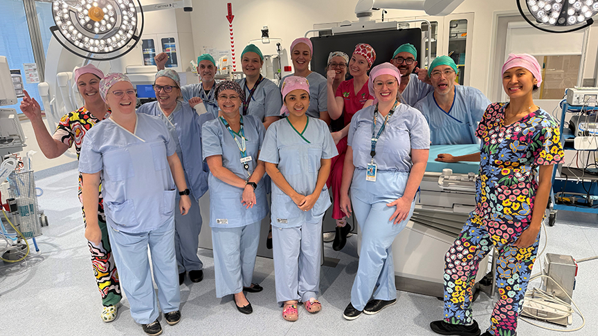 Group photo of clinical staff in scrubs standing in operating room