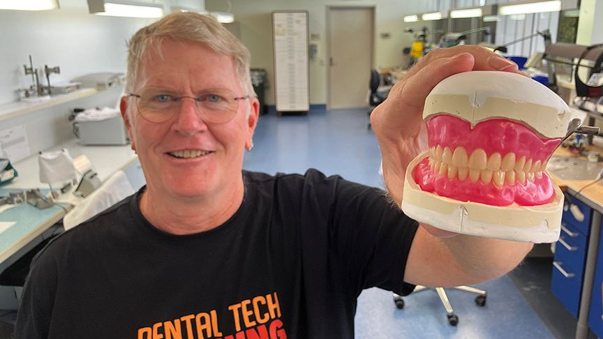 Man holding up dentures towards the camera