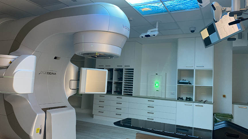 Large white linear accelerator in clinical room